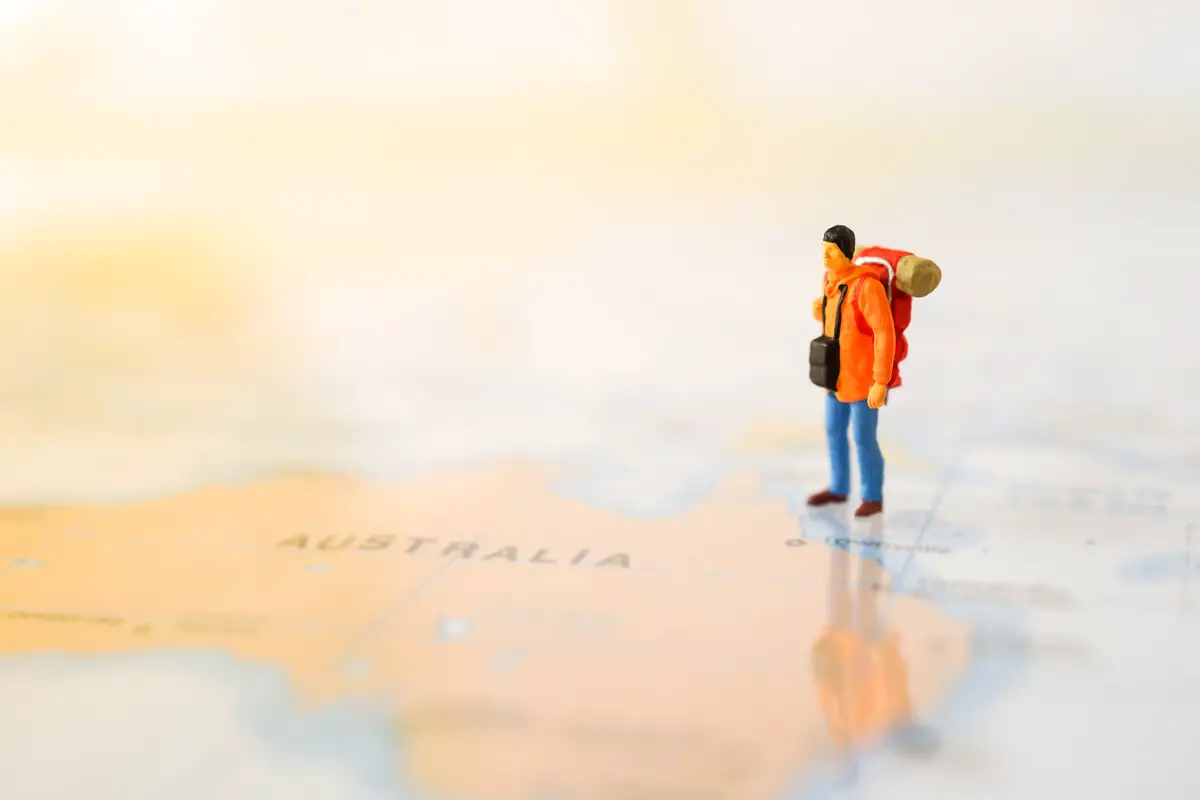 A lonely backpacker visiting Australia pictured as figurine on a map.