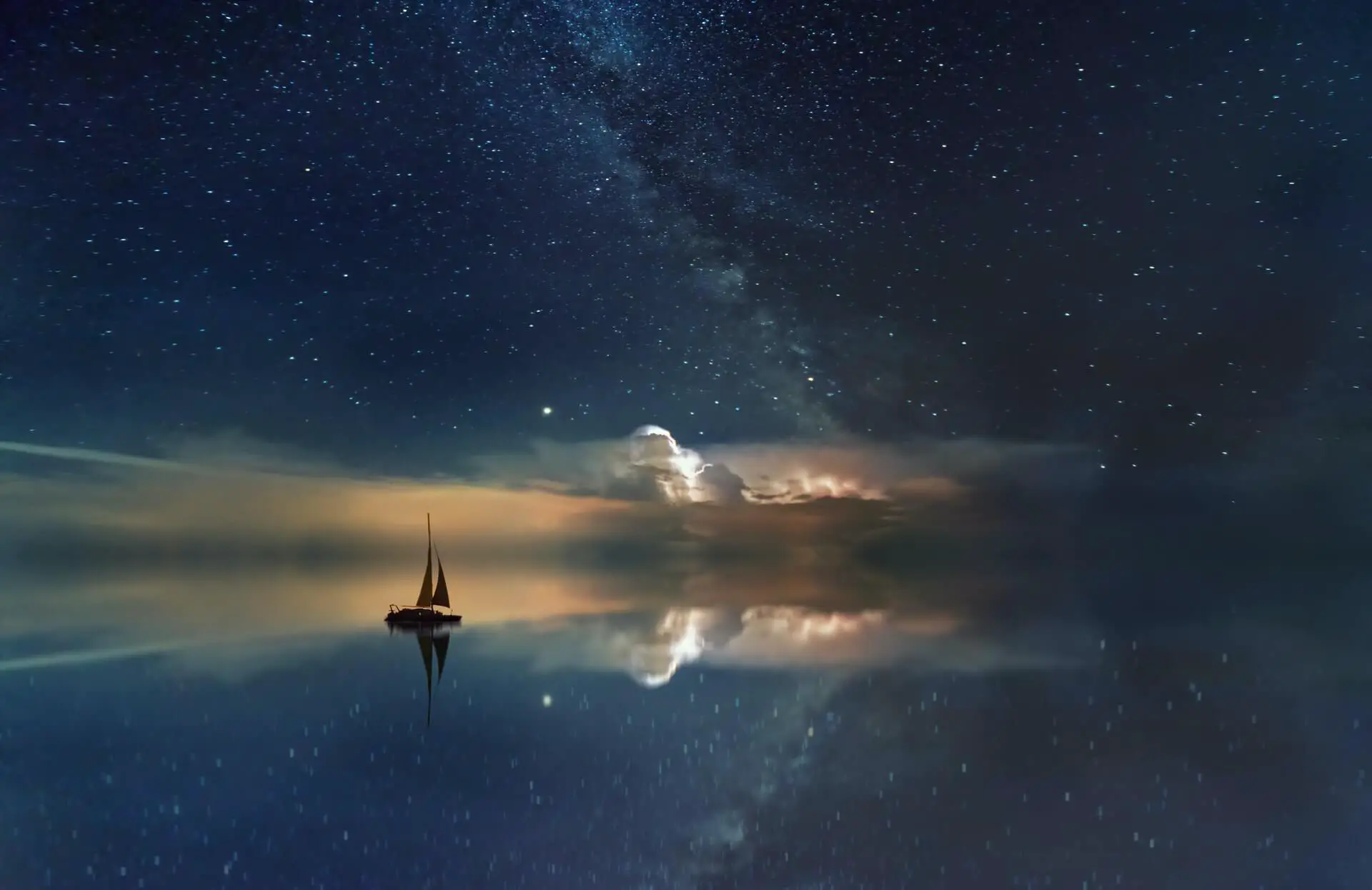 A sailboat travelling Oceania on the Pacific Ocean on a starry night.