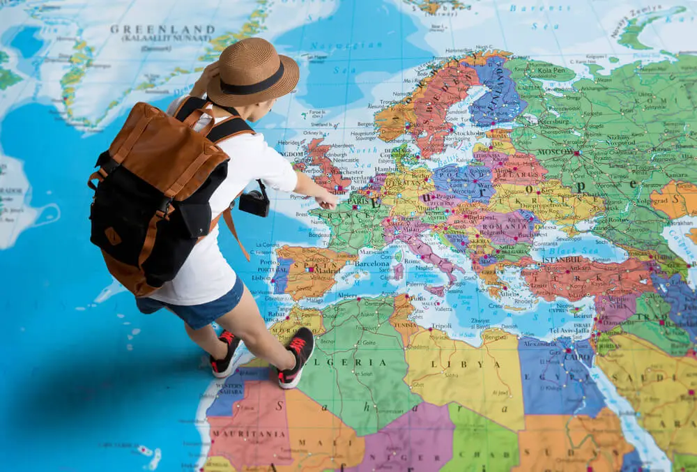 A woman backpacking Greece chooses her onwards travels in Europe with a map
