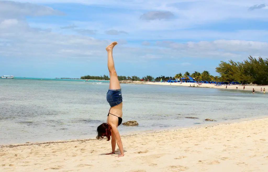 solo female traveller doing a handstand on a beach in Bahamas