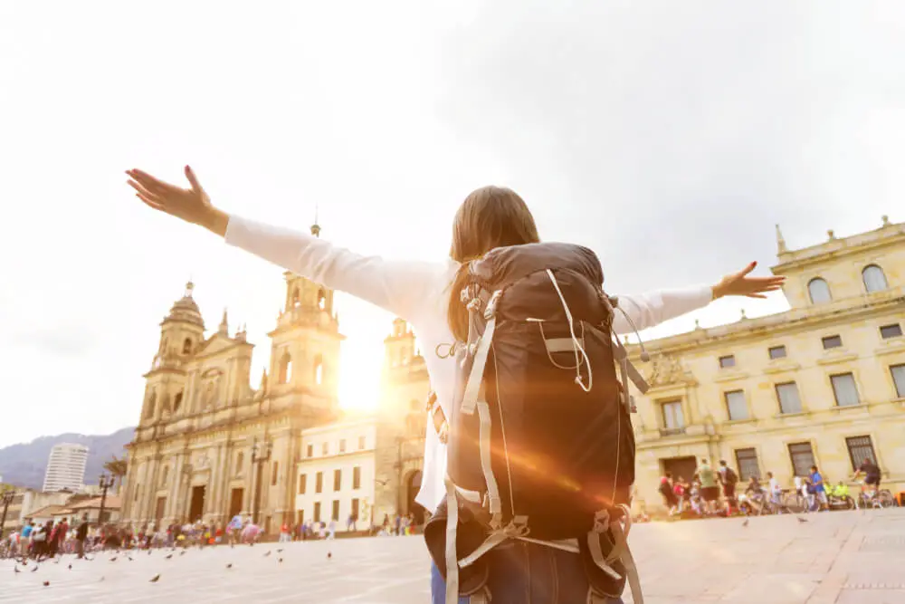 solo female traveller standing on a square in Colombia with her arms outstretched