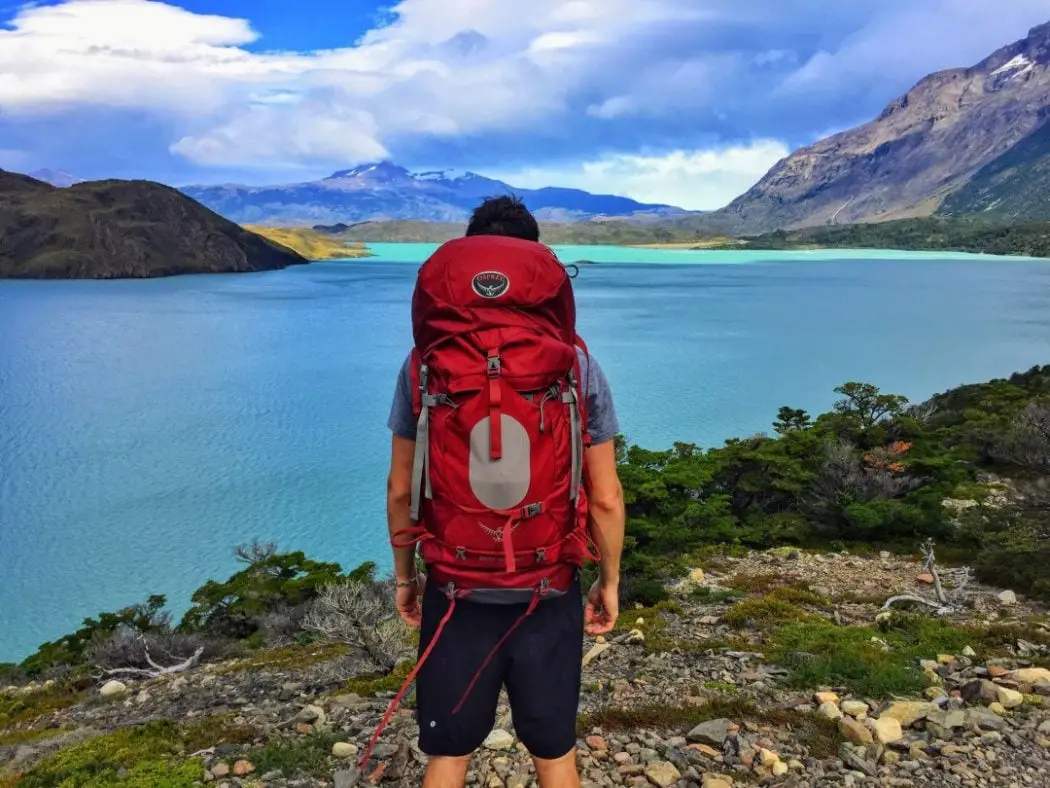 a man with his best travel backpack surveys a lake
