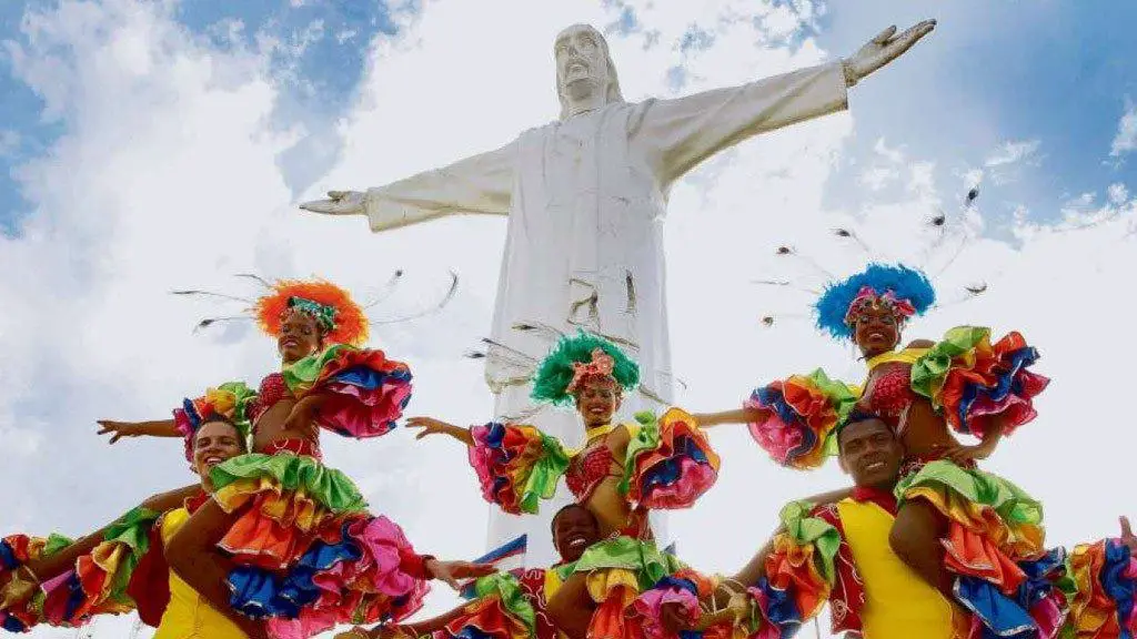 A statue of Jesus looks down on dancers in colombia