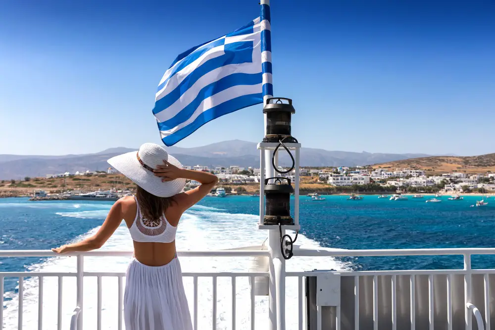A female tourist in Greece catches a public ferry with the Greek flag